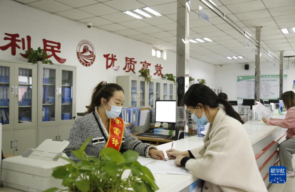 河北省邢臺市襄都區宴家屯鎮綜合服務中心工作人員協助辦事群眾填寫相關表格（2022年3月30日攝）。