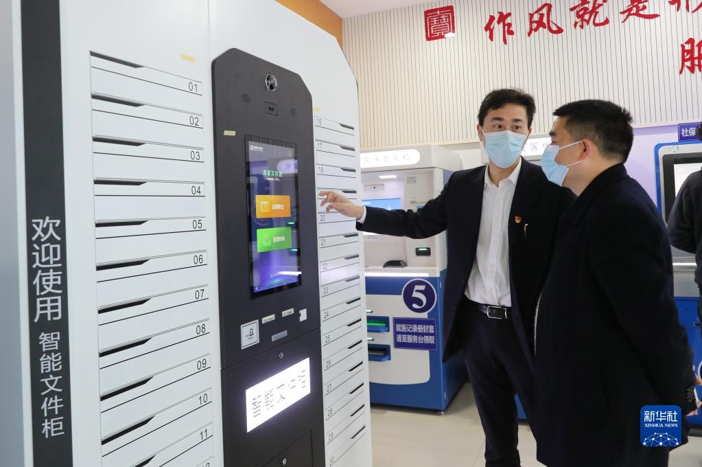 上海市閔行區七寶鎮社區事務受理服務中心的工作人員（左）向前來辦事的居民介紹智能文件柜的使用方法（2021年3月3日攝）。